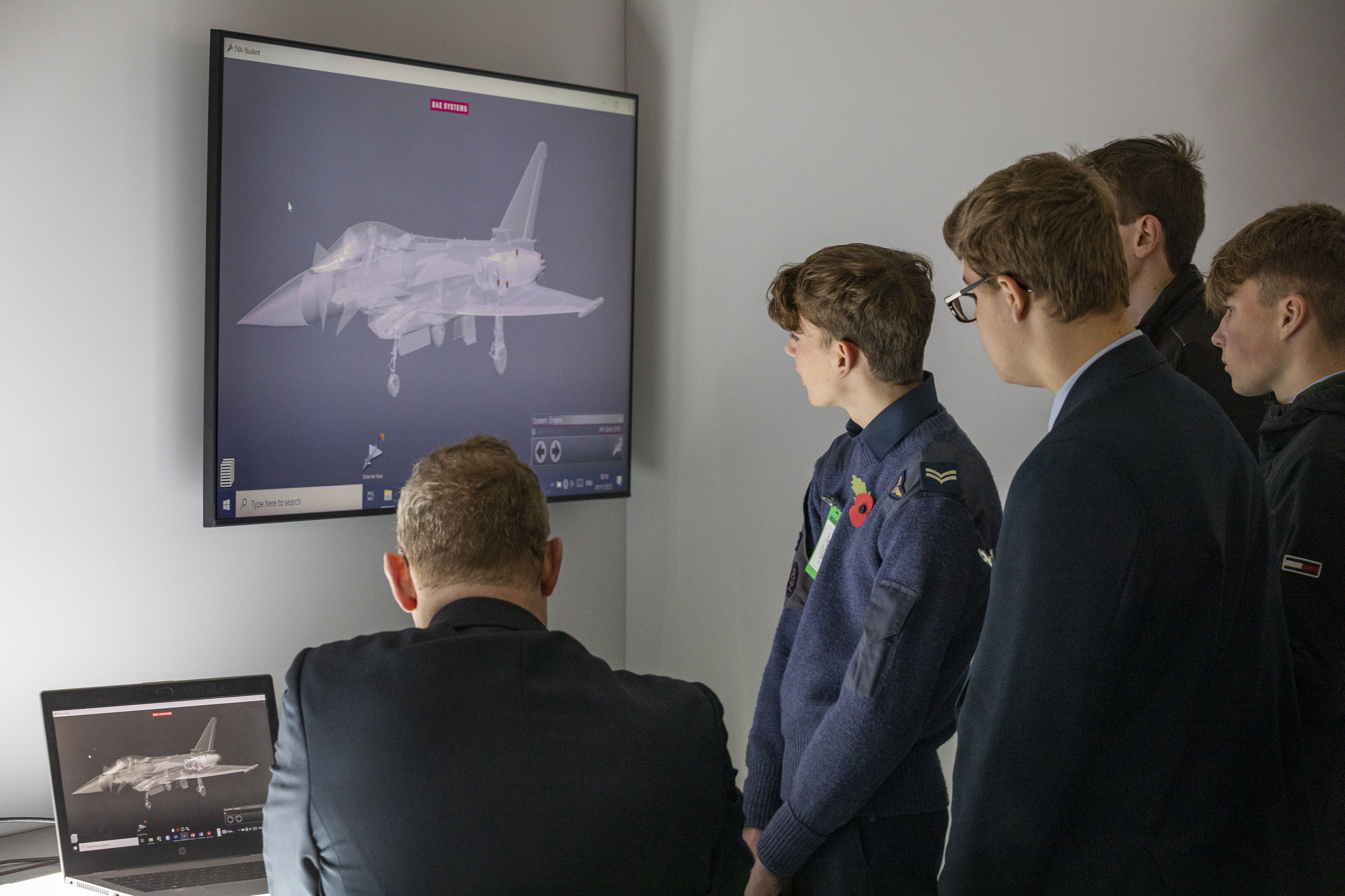 Image shows young people and personnel looking at 3 d model of typhoon on a screen.